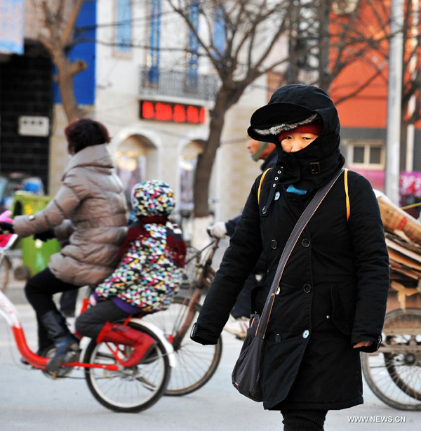 A local resident walks in chill wind in Baoding, north China's Hebei Province, Dec. 23, 2012. The provincial meteorological observatory issued a blue alert on cold wave on Saturday. Most parts of Hebei suffered from a sharp decline of temperatures and strong wind.