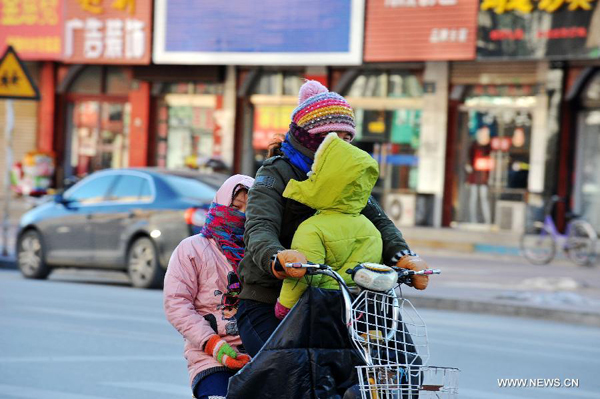 A local resident rides in chill wind in Baoding, north China's Hebei Province, Dec. 23, 2012. The provincial meteorological observatory issued a blue alert on cold wave on Saturday. Most parts of Hebei suffered from a sharp decline of temperatures and strong wind.