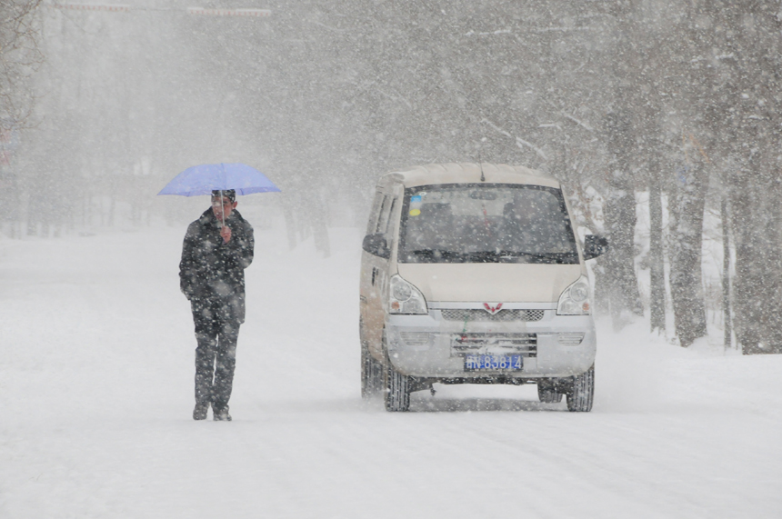 A pedestrian and a vehicle move in snow on Hetie highway in Hezheng County of Linxia Hui Autonomous Prefecture, northwest China&apos;s Gansu Province, Dec. 28, 2012. Strong wind and heavy snowfall hit most parts of Gansu Province on Friday.