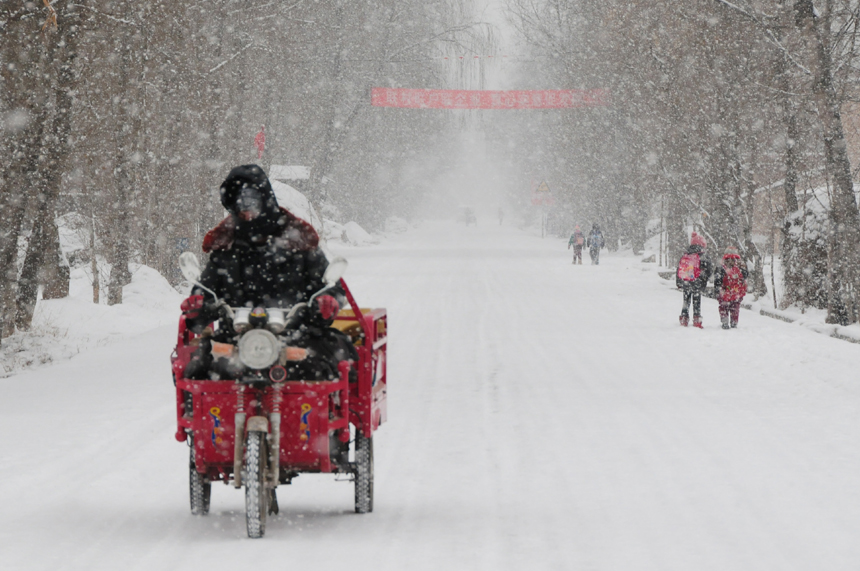 Pedestrians and a vehicle move in snow on Hetie highway in Hezheng County of Linxia Hui Autonomous Prefecture, northwest China&apos;s Gansu Province, Dec. 28, 2012. Strong wind and heavy snowfall hit most parts of Gansu Province on Friday. 