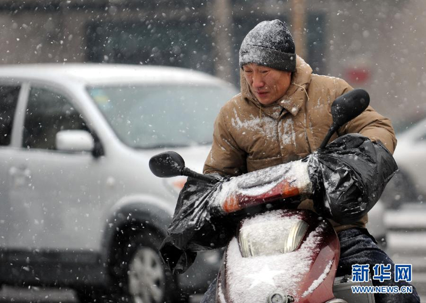 A pedestrian and a vehicle move in snow in Shenyang, Liaoning Province, Dec. 28, 2012. Strong wind and heavy snowfall hit many parts of north China on Friday. 