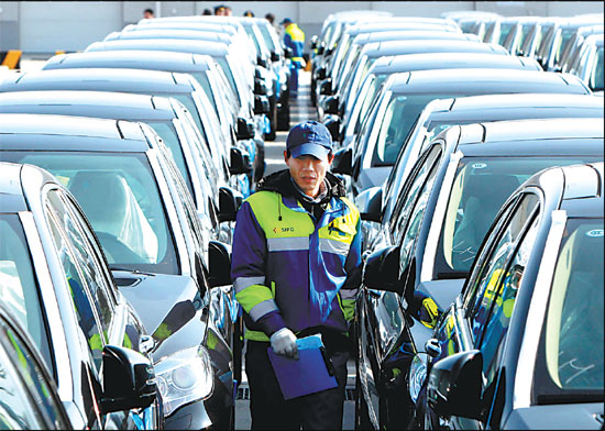 An inspector walks among imported vehicles at Shanghai's Waigaoqiao port. China imported 79,800 vehicles in November, down 26.1 percent year-on-year. [Xinhua]