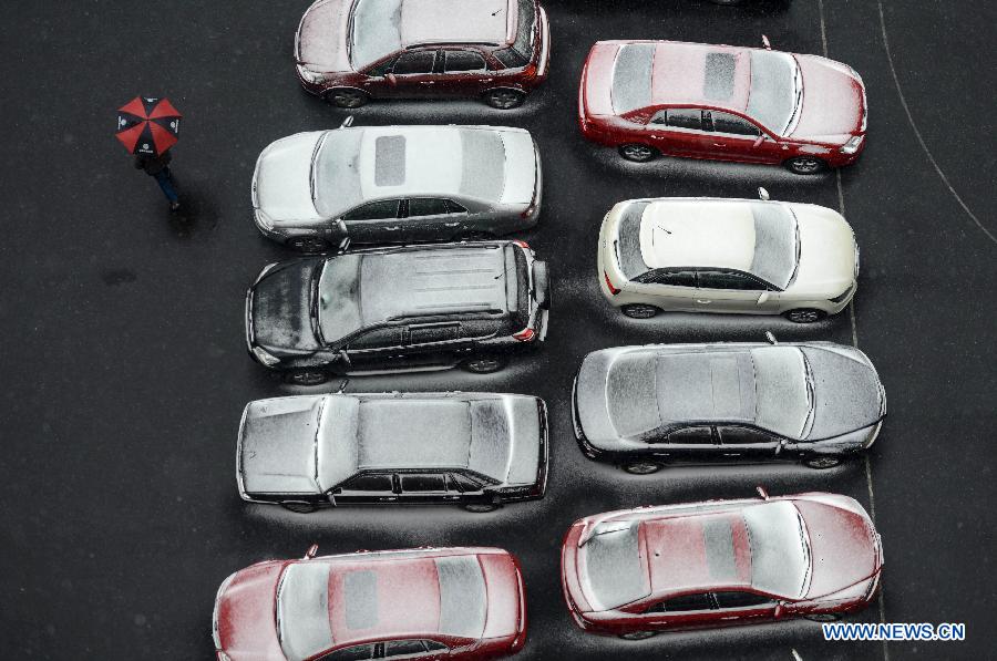 A pedestrian walks past an array of snow-covered cars in Hangzhou, capital of east China's Zhejiang Province, Jan. 3, 2013. The central and northern parts of Zhejiang witnessed on Thursday the first snow in 2013. 