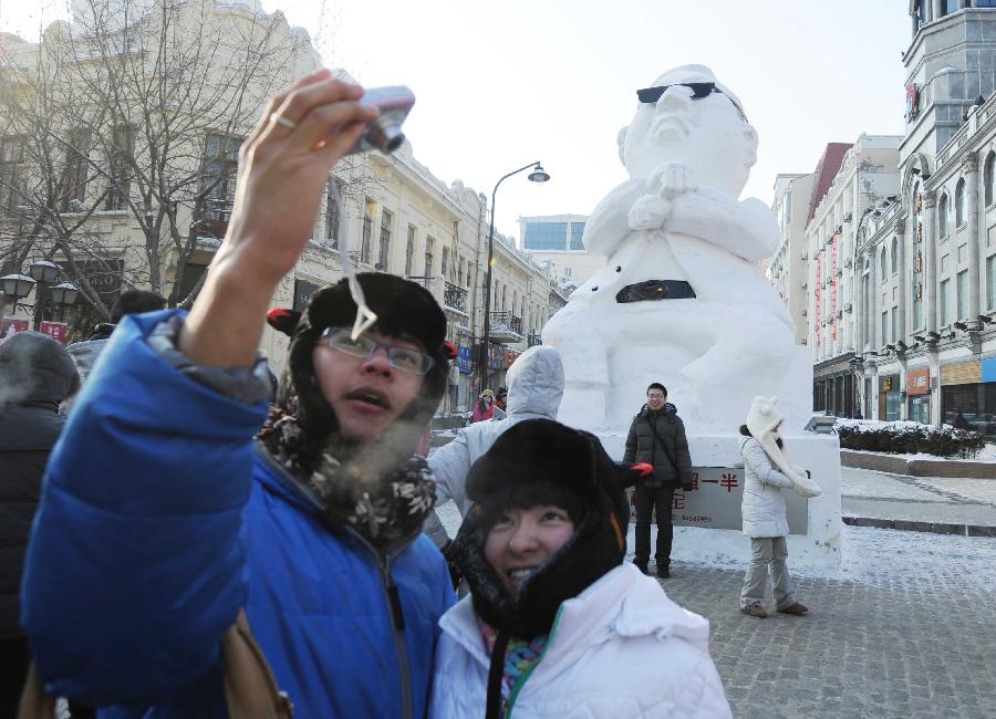 Tourists pose for photo in front of a snow sculpture of South Korean rapper Psy in Harbin, capital of northeast China's Heilongjiang Province, Jan. 2, 2013. Psy's music video of 'Gangnam Style,' featuring the horse-riding dance, became a global sensation this year. (Xinhua/Wang Jianwei) 
