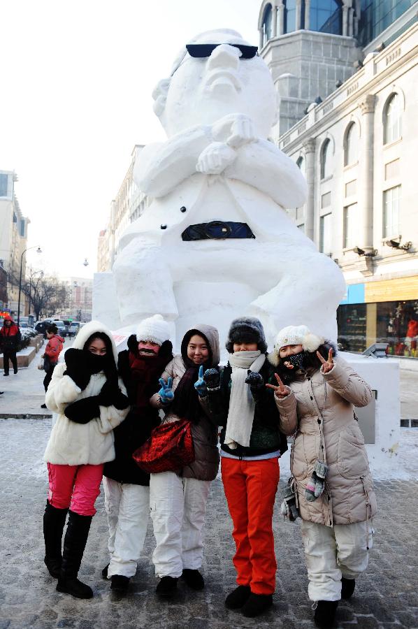 Tourists pose for photo in front of a snow sculpture of South Korean rapper Psy in Harbin, capital of northeast China's Heilongjiang Province, Jan. 2, 2013. Psy's music video of 'Gangnam Style,' featuring the horse-riding dance, became a global sensation this year. (Xinhua/Wang Jianwei) 