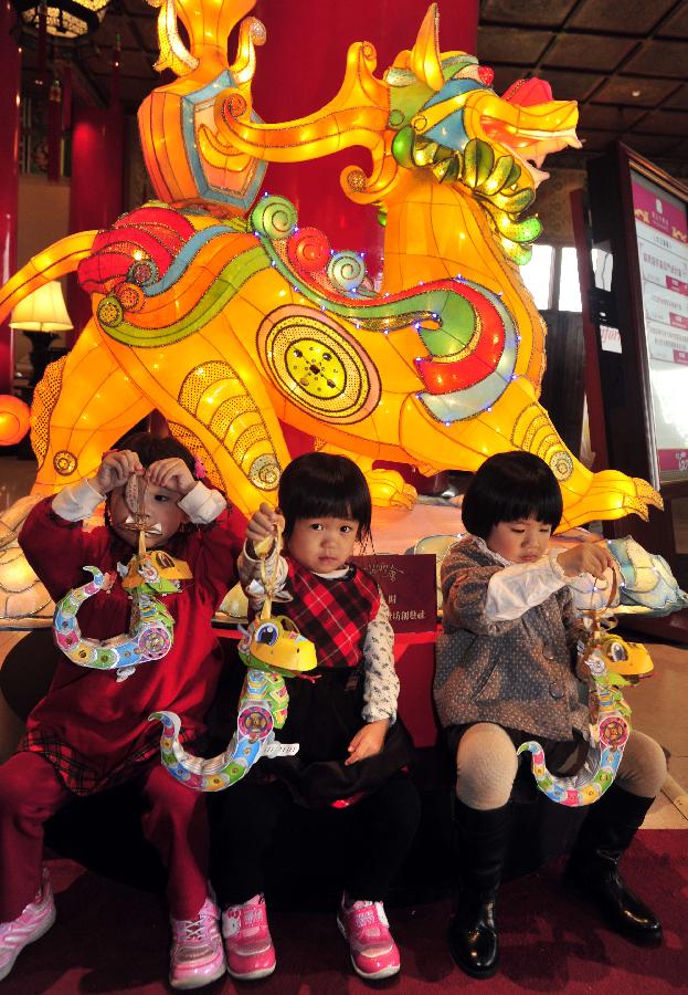 Children play with the small hand lanterns featuring a cartoon snake during a news conference at the Grand Hotel in Taipei, southeast China's Taiwan, Jan. 4, 2013. The conference held on Friday was to issue the shapes of the main lantern and small hand lantern of 2013 Taiwan Lantern Festival. The festival will kick off in Taipei on Feb. 24. (Xinhua/Wu Ching-teng)