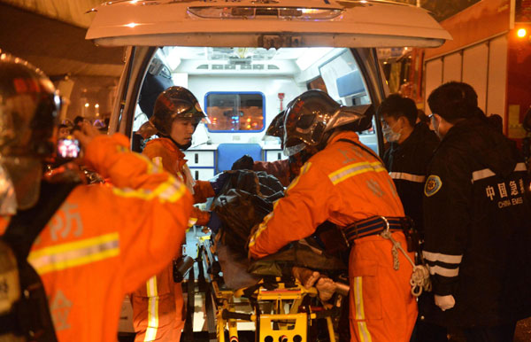 Firefighters carry one of the injured onto an ambulance after fire broke out at a farm produce wholesale market in Shanghai on Jan 6, 2013. [Photo/Xinhua] 