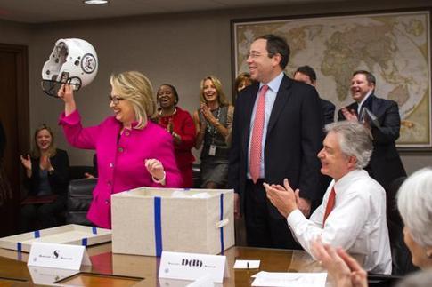 This photo provided by the United States Department of State shows Secretary of State Hillary Rodham Clinton holding up a football helmet presented to her at the State Department in Washington, Monday, Jan. 7, 2013.