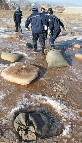 Workers from the Lu'an Group, parent company of the Tianji Coal Chemical Industry Group, use activated carbon to clean aniline from the Huangniuti Reservoir in Lucheng, Shanxi, on Wednesday. [Photo/China Daily]