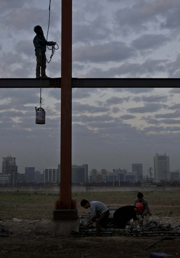 Steel frame painters work high on a building in Jiaxing city, Zhejiang province Nov 29, 2012. [Photo/CFP]
