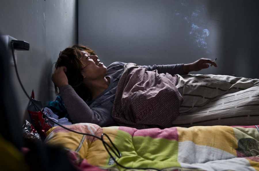 Cheng Liang, a steel frame painter, smokes in bed before getting up on Dec 6 in Jiaxing city, Zhejiang province. [Photo/CFP]