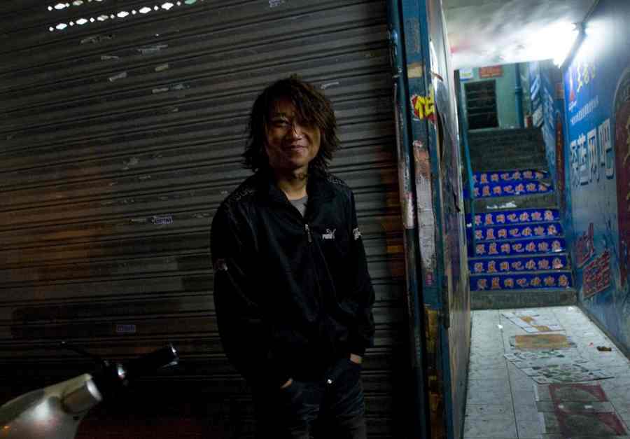 Chen Liang, a steel frame painter, stands outside an Internet bar in Jiaxing city, Zhejiang province, on Dec 7, 2011. [Photo/CFP]