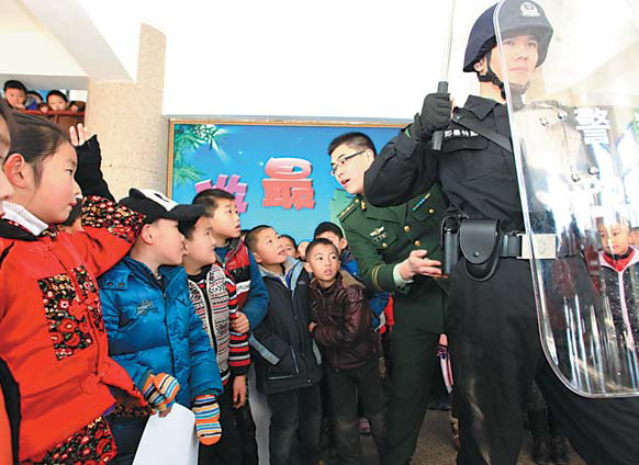 Officers from the Armed Police and local public security bureau in Jimo, East China’s Shandong province, display policing skills to students at the No 3 Experimental Primary School on Thursday. Jan 10 is the 110 Police Hotline Awareness Day in China. [Photo/China Daily]