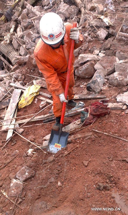 A rescuer works at the landslide site at Gaopo Village of Zhenxiong County, southwest China's Yunnan Province, Jan. 11, 2013. More than 10 residential houses with over 40 people were buried after a landslide happened at the village early Friday morning, according to local officials.