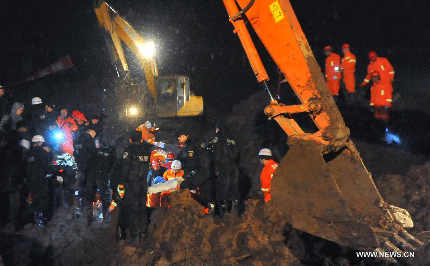 Rescuers and an excavator work at the mud-inundated debris after a landslide hit Gaopo Village in Zhenxiong County, southwest China&apos;s Yunnan Province, Jan. 11, 2013.