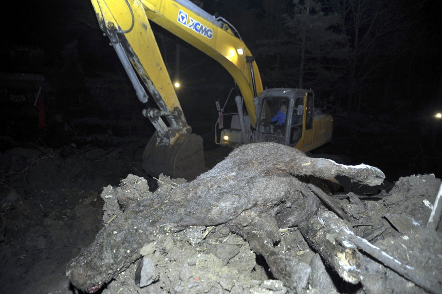 An excavator works at the mud-inundated debris after a landslide hit Gaopo Village in Zhenxiong County, southwest China&apos;s Yunnan Province, Jan. 12, 2013. 