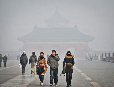 Tourists wearing facemasks walk by the Temple of Heaven in Beijing, as Saturday's PM 2.5 air quality index reached around 470-490. [Xinhua] 