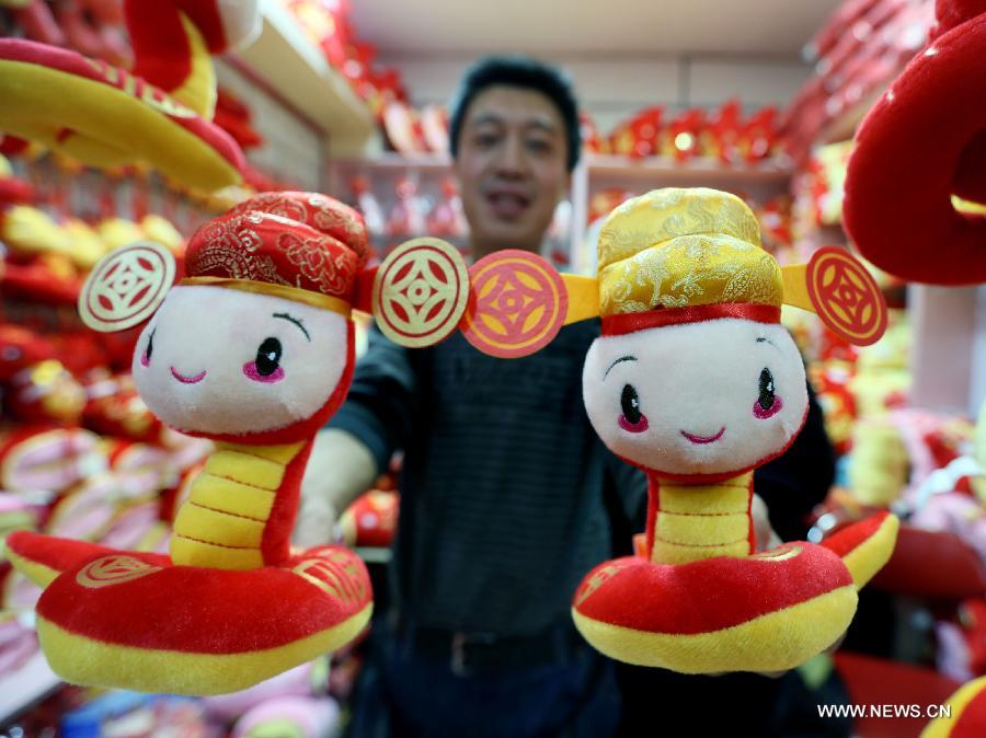 A man displays two cartoon figures of snakes at Tianyi small commodities market in Beijing, capital of China. Jan. 13, 2013