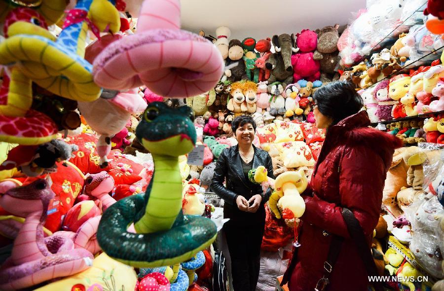 A saleswoman introduces a cartoon figure of snake at Tianyi small commodities market in Beijing, capital of China. Jan. 13, 2013