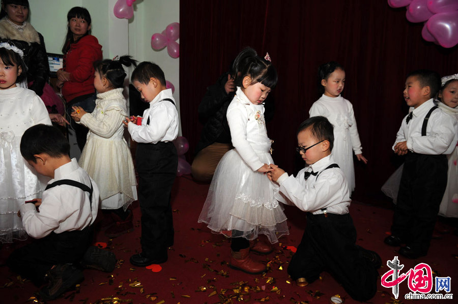 2013年1月11日，河南郑州，图为小“新郎”们很绅士的单膝跪倒，给自己的小“新娘”戴上结婚戒指。[张翼飞/CFP]