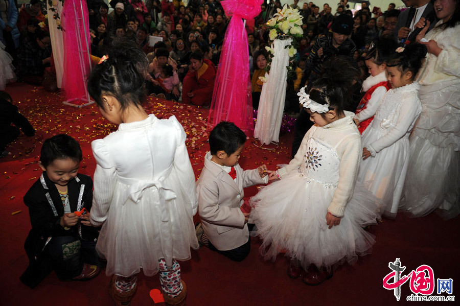2013年1月11日，河南郑州，图为小“新郎”们很绅士的单膝跪倒，给自己的小“新娘”戴上结婚戒指。[张翼飞/CFP]