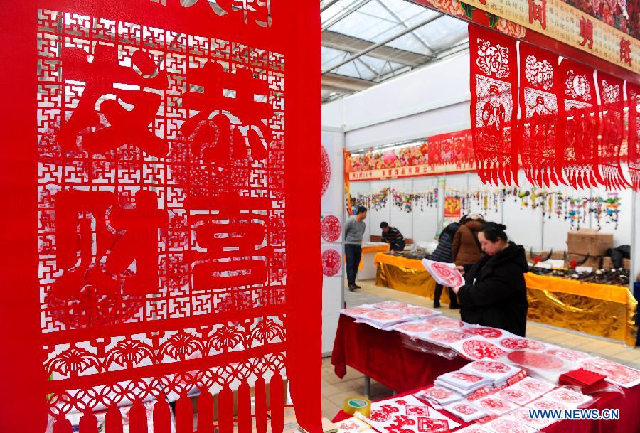 Visitors select paper-cut artworks during the 4th Jilin Agricultural Expo for Winter in Changchun, capital of northeast China's Jilin Province, Jan. 16, 2013.