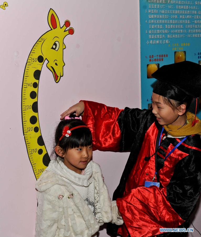 A working staff helps a girl measure her height at the science experience hall for youths in the Heilongjiang Museum in Harbin, capital of northeast China's Heilongjiang Province, Jan. 15, 2013. 