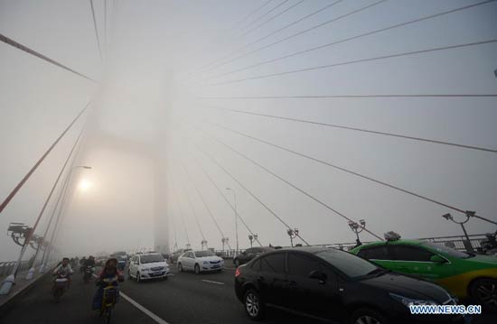 Motorcars run on the Bayi Bridge amid heavy fog in Nanchang, capital of east China's Jiangxi Province, Jan. 14, 2013. Nanchang's air has been heavily polluted for five days in a row, according to local meteorological authorities. [Xinhua/Zhou Ke] 