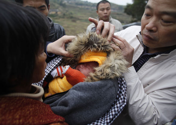 A woman holding a baby boy she bought from child traffi ckers is stopped by plainclothes police officers in Anxi county, Quanzhou, Fujian province, in December. Public security authorities rescued 89 abducted children and arrested 355 suspects in a nationwide crackdown on children traffi cking in December. [Photo/Xinhua]