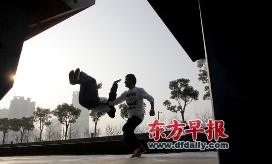 昨天，在徐汇滨江大道，两个青年在阳光下做街舞翻身动作。早报记者 张栋 图