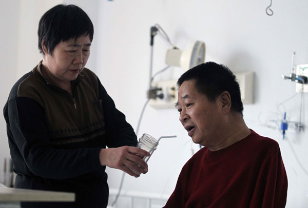 Mao Dahua cares for her husband Liu Jingsheng, an armless Beijing artist, at a hospital in the city on Saturday. Suffering from kidney failure and unable to undergo dialysis, Liu is looking for kidney donation to save his life. [Photo/China Daily] 