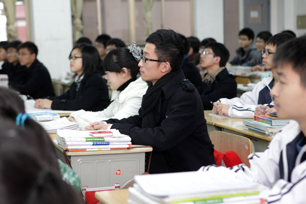 Anhui native Liu Peng (right) takes notes in class in a private high school in Zhejiang province. He no longer needs to spend extra time studying textbooks used in his hometown after the province’s new gaokao rules allow students without local hukou to attend the entrance exam in Zhejiang. [Photo/China Daily]