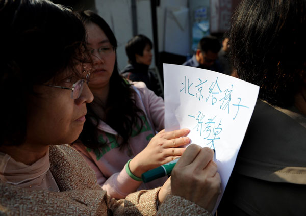 A mother asks for her child to have the right to take the national college entrance examination in Beijing. Parents of migrant children without Beijing hukou gather at the gate of the capital’s education commission to check for updates of the gaokao rules. [PROVIDED TO CHINA DAILY] 