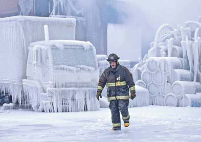 Chicago Fire Department Lieutenant Charley De Jesus walks around an ice-covered warehouse that caught fire on Tuesday night in Chicago on Wednesday. [Agencies]