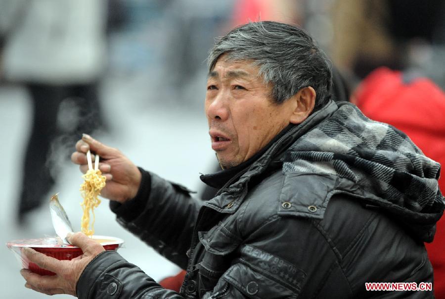 A passenger eats instant noodles at the waiting hall of railway station in Shenyang, capital of northeast China's Liaoning Province, Jan. 26, 2013. The 40-day Spring Festival travel rush started Saturday. [Yang Xinyue/Xinhua]