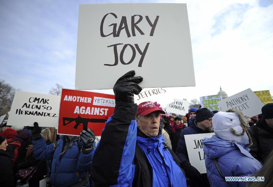 People hold signs with names of gun violence victims in front of the Capitol Hill during a march in Washington D.C., capital of the United States, Jan. 26, 2013. Thousands of people, including family members of victims and survivors of shootings at Virginia Tech University, Sandy Hook elementary school and others, took part in a march for stricter gun control laws here on Saturday. [Zhang Jun/Xinhua]