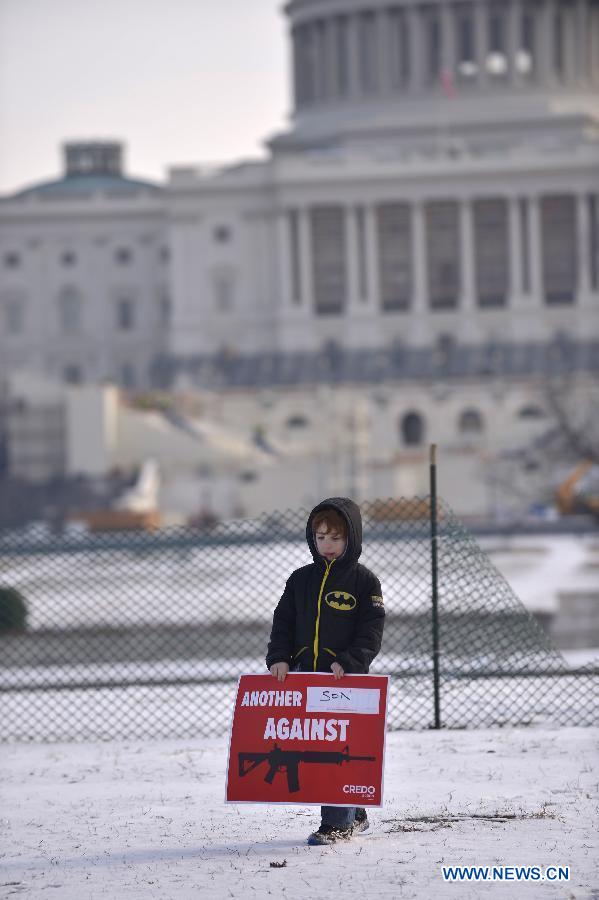 Six-year-old Dylan Wolos holds a sign against gun violence in front of the Capiotl Hill during a march in Washington D.C., capital of the United States, Jan. 26, 2013. Thousands of people, including family members of victims and survivors of shootings at Virginia Tech University, Sandy Hook elementary school and others, took part in a march for stricter gun control laws here on Saturday. [Zhang Jun/Xinhua]