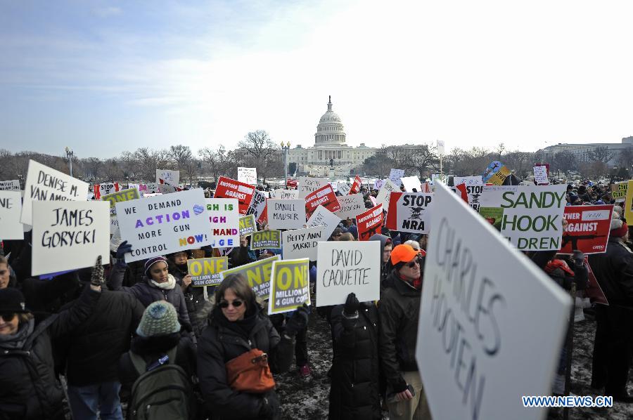 People hold signs with names of gun violence victims in front of the Capitol Hill during a march in Washington D.C., capital of the United States, Jan. 26, 2013. Thousands of people, including family members of victims and survivors of shootings at Virginia Tech University, Sandy Hook elementary school and others, took part in a march for stricter gun control laws here on Saturday. [Zhang Jun/Xinhua]