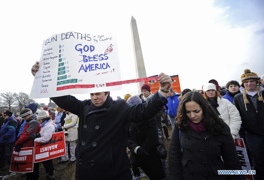 People hold signs against gun violence in front of the Washington Monument during a march in Washington D.C., capital of the United States, Jan. 26, 2013. Thousands of people, including family members of victims and survivors of shootings at Virginia Tech University, Sandy Hook elementary school and others, took part in a march for stricter gun control laws here on Saturday. [Zhang Jun/Xinhua]