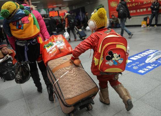 A girl from southwest China's Guizhou Province follows her mother into Hangzhou train station to wait for their train home in Hangzhou, capital of east China's Zhejiang Province, Jan. 22, 2013.