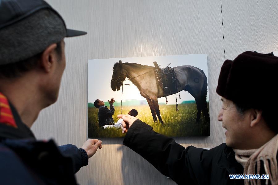 Visitors watch a photography work during Inner Mongolia Ecology Photographs Exhibition in Beijing, capital of China, Jan. 28, 2013. (Xinhua/Zheng Huansong)