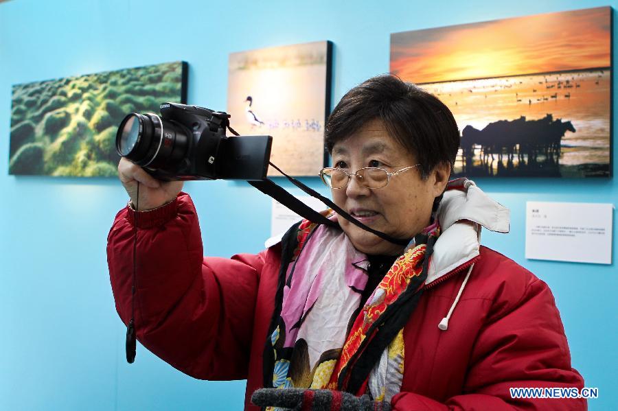 An amateur photographer takes photos during Inner Mongolia Ecology Photographs Exhibition in Beijing, capital of China, Jan. 28, 2013. (Xinhua/Zheng Huansong)