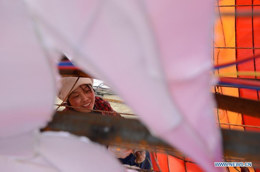 A woman works on a lantern on the street in Nanchang, capital of east China's Jiangxi Province, Jan. 28, 2013. Lanterns designed in Zigong of southwest China's Sichuan Province will meet with the residents here during the upcoming Spring Festival holidays. (Xinhua/Zhou Mi) 