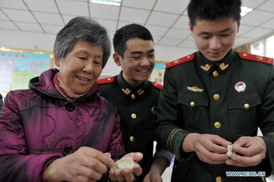 Li Jiazhen (L), a retired staff member, teaches firefighters to make dumplings at a fire brigade in Wulidun Community of Hefei, capital of east China's Anhui Province, Jan. 30, 2013. A group of community workers and retired staff members visited Wulidun fire brigade to celebrate the upcoming Spring Festival with the firefighters here on Wednesday. (Xinhua/Guo Chen) 