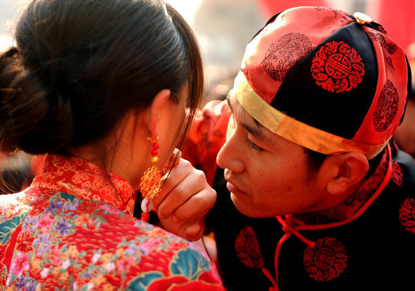 A groom helping his bride to finish her makeup before their wedding ceremony in Zhengzhou, the capital of Central China's Henan province. [Photo/China Daily]