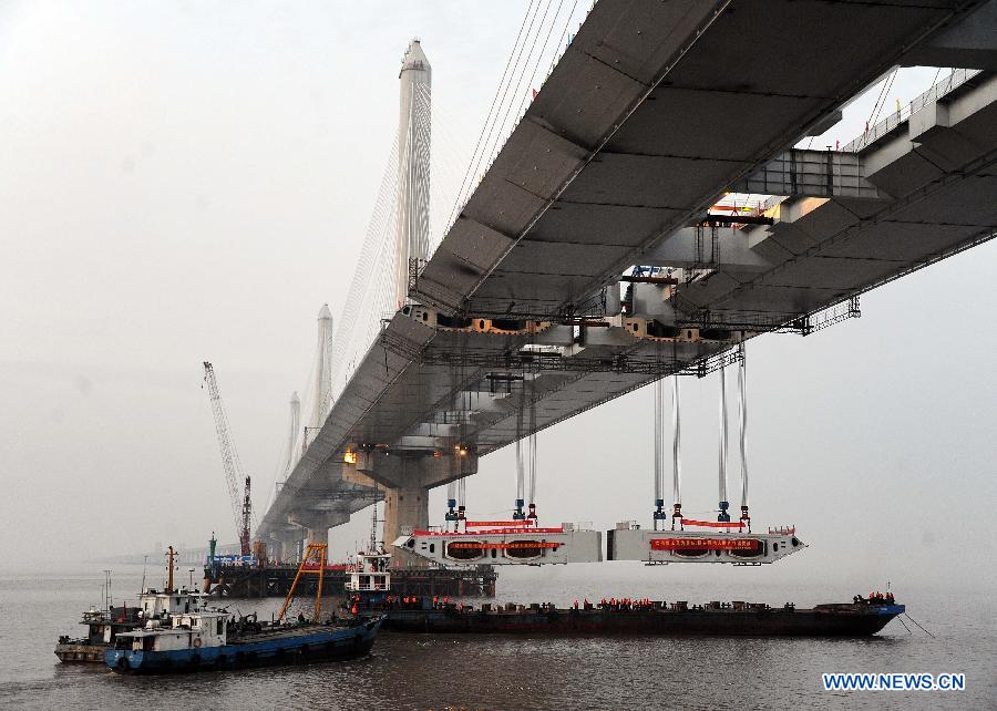 Photo taken on Feb. 3, 2013 shows the last two steel box girders, each of which weighs 408 tons, are lifted up to the floor of the Jiaxing-Shaoxing Sea-Crossing Bridge in Shaoxing, east China's Zhejiang Province. 