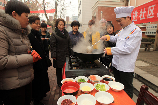 A restaurant chef teaches residents how to make dishes for Chinese New Year's Eve at a community in Xuchang, Henan province, on Wednesday. [Photo/China Daily]