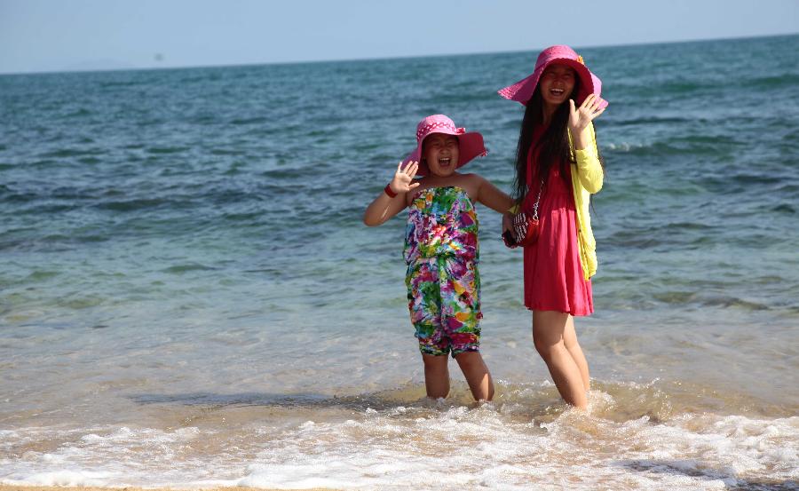 Tourists enjoy sunshine at seaside in Sanya