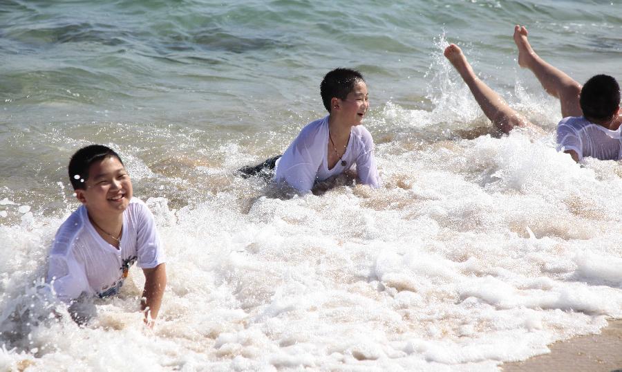 Tourists enjoy sunshine at seaside in Sanya