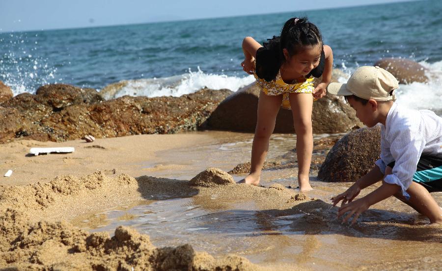 Tourists enjoy sunshine at seaside in Sanya